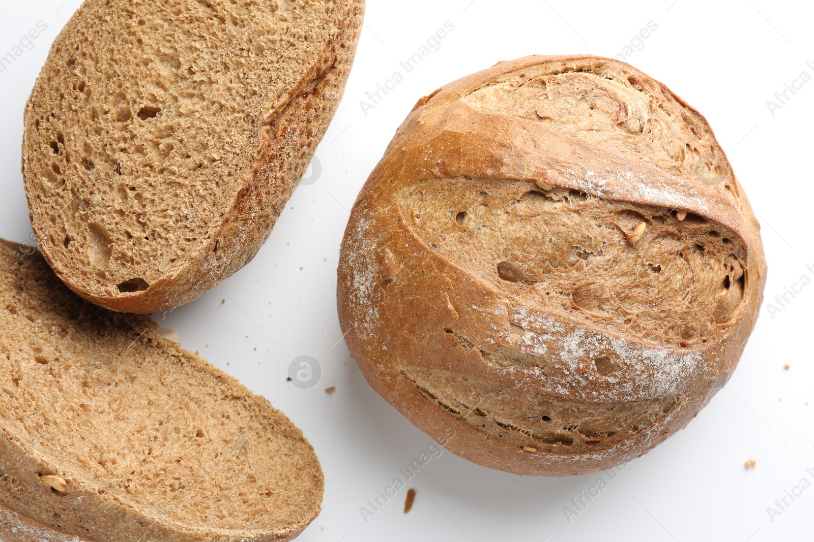 Photo of Whole and halves of freshly baked bread on white background, flat lay