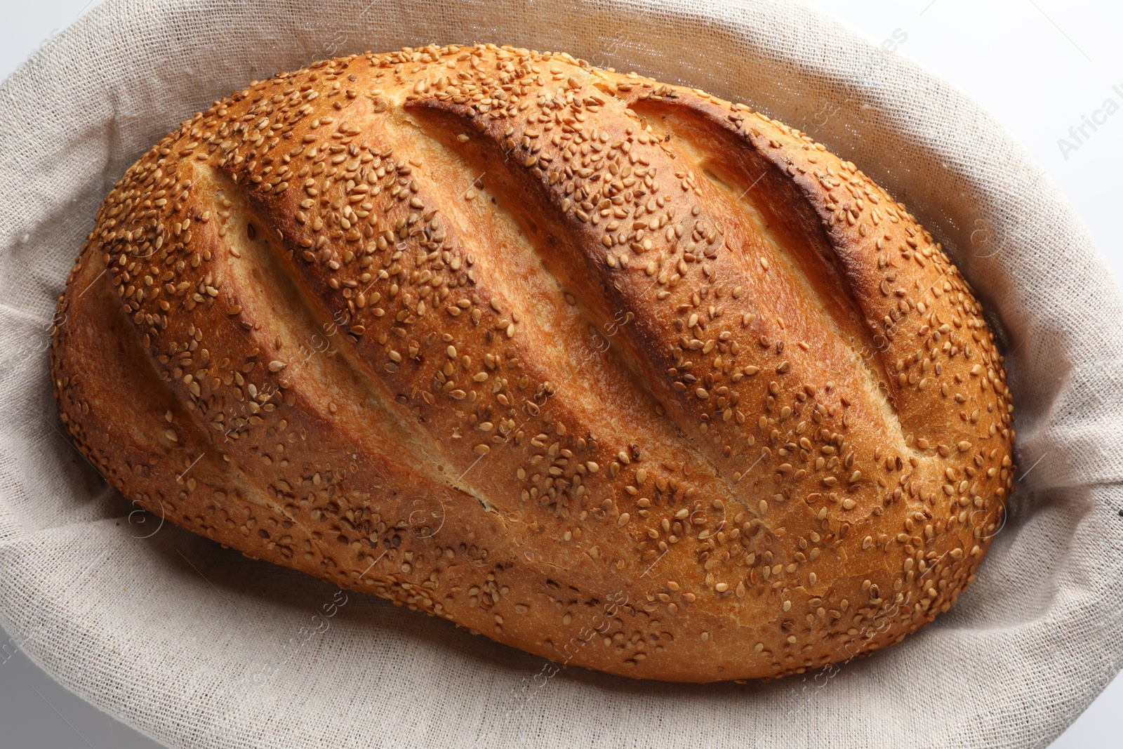 Photo of Freshly baked bread with seeds in basket on white background, above view