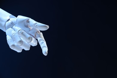 Photo of Artificial intelligence. Robot hand pointing at something on dark blue background, space for text