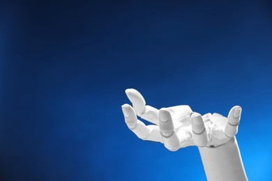 Photo of Artificial intelligence. Robot hand gesturing on dark blue background, space for text