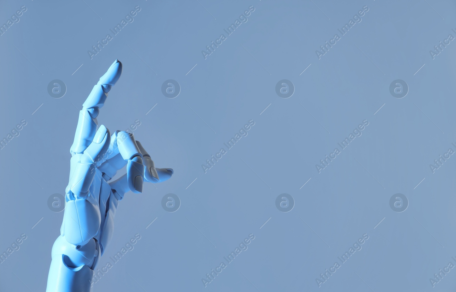 Photo of Artificial intelligence. Robot hand pointing at something on pale light blue background, space for text