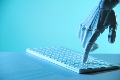 Photo of Artificial intelligence. Robot hand using keyboard at table in blue light, closeup. Space for text