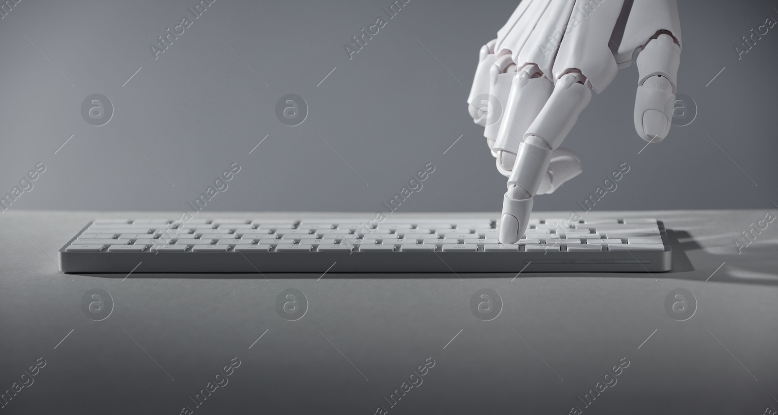 Photo of Artificial intelligence. Robot hand using keyboard on grey background closeup