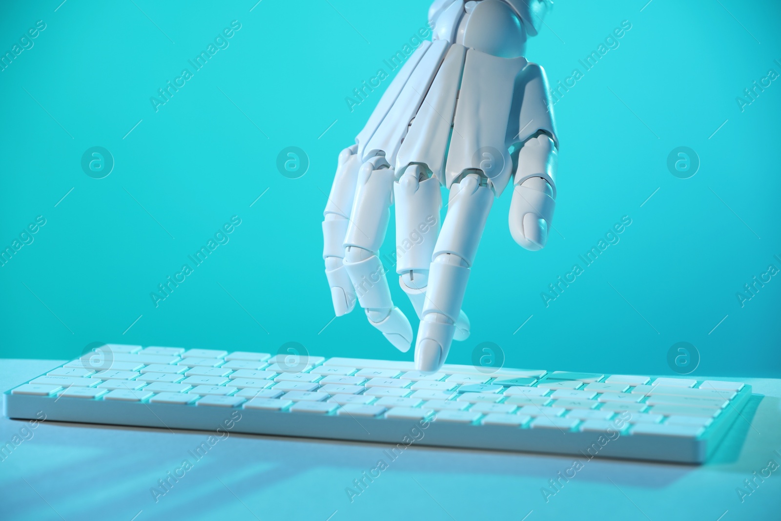 Photo of Artificial intelligence. Robot hand using keyboard at table in blue light, closeup