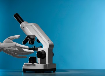 Photo of Artificial intelligence. Robot hand working with microscope at grey table against blue background, space for text