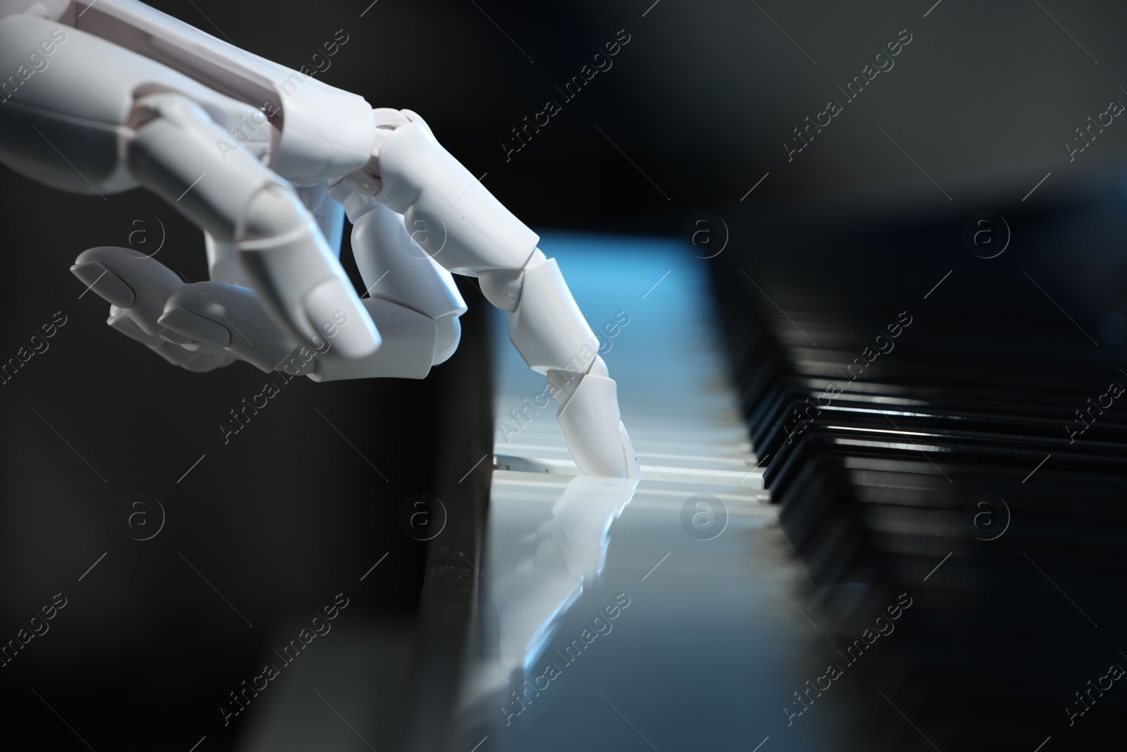 Photo of Artificial intelligence. Robot hand playing piano on dark background, closeup