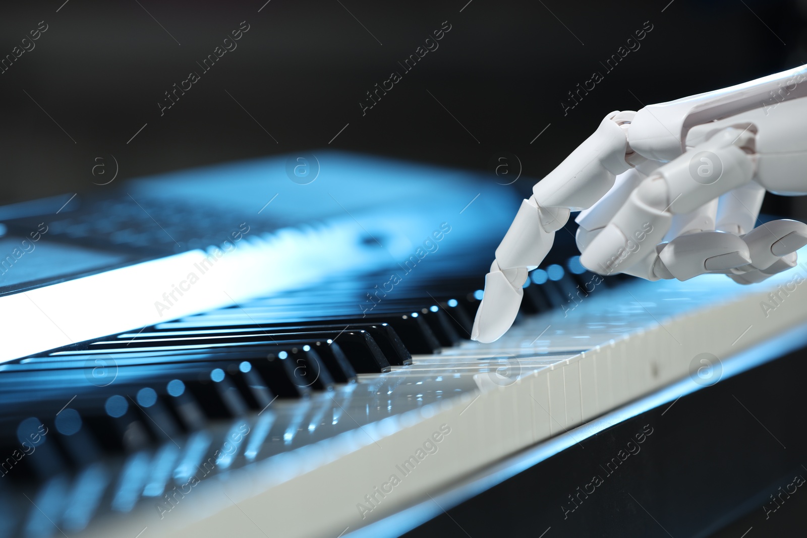 Photo of Artificial intelligence. Robot hand playing piano on dark background, closeup