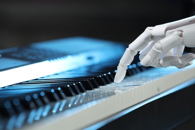 Photo of Artificial intelligence. Robot hand playing piano on dark background, closeup