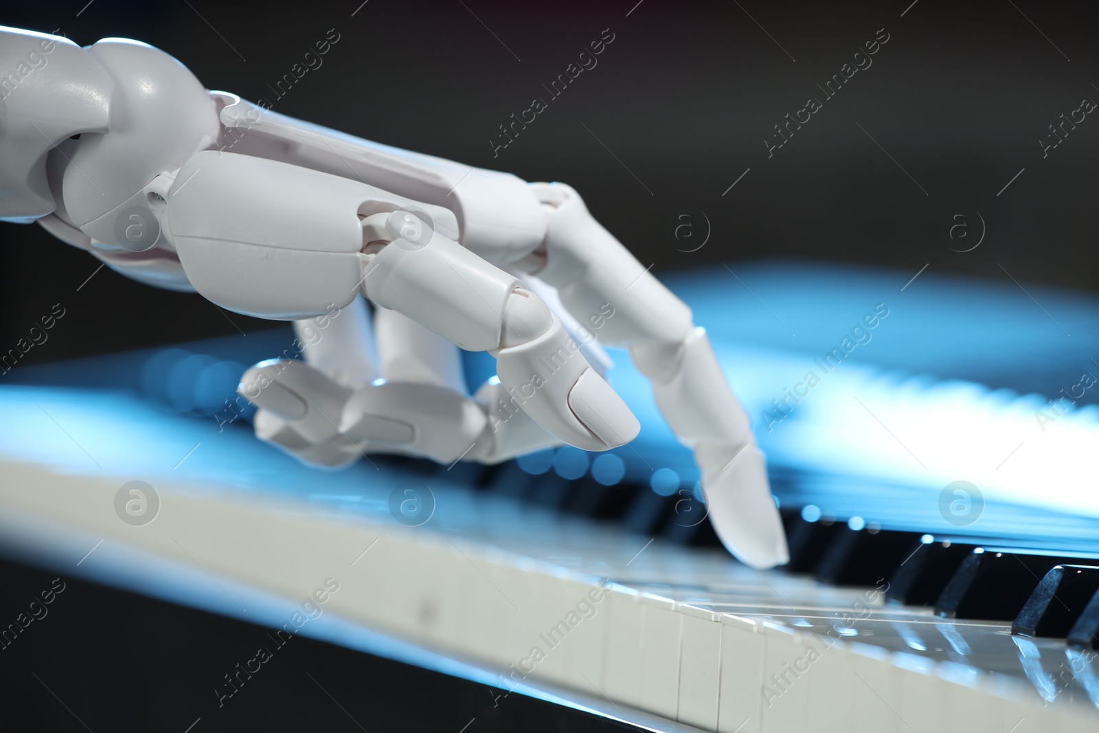 Photo of Artificial intelligence. Robot hand playing piano on dark background, closeup