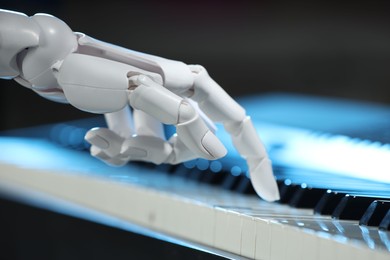 Photo of Artificial intelligence. Robot hand playing piano on dark background, closeup