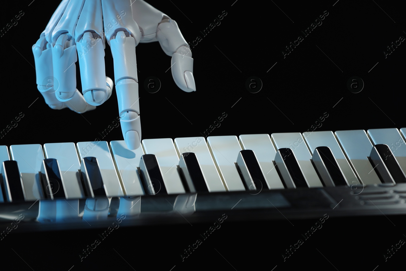 Photo of Artificial intelligence. Robot hand playing synthesizer on black background, closeup