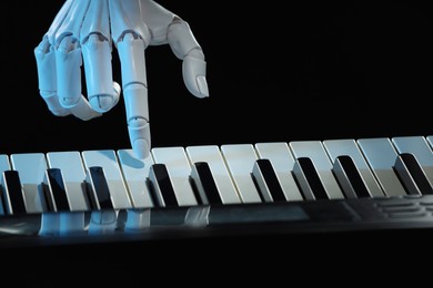 Photo of Artificial intelligence. Robot hand playing synthesizer on black background, closeup