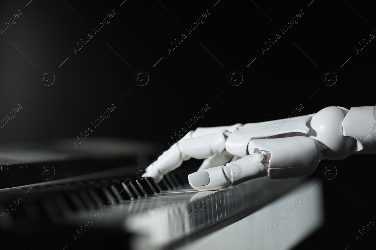 Photo of Artificial intelligence. Robot hand playing piano on black background, closeup