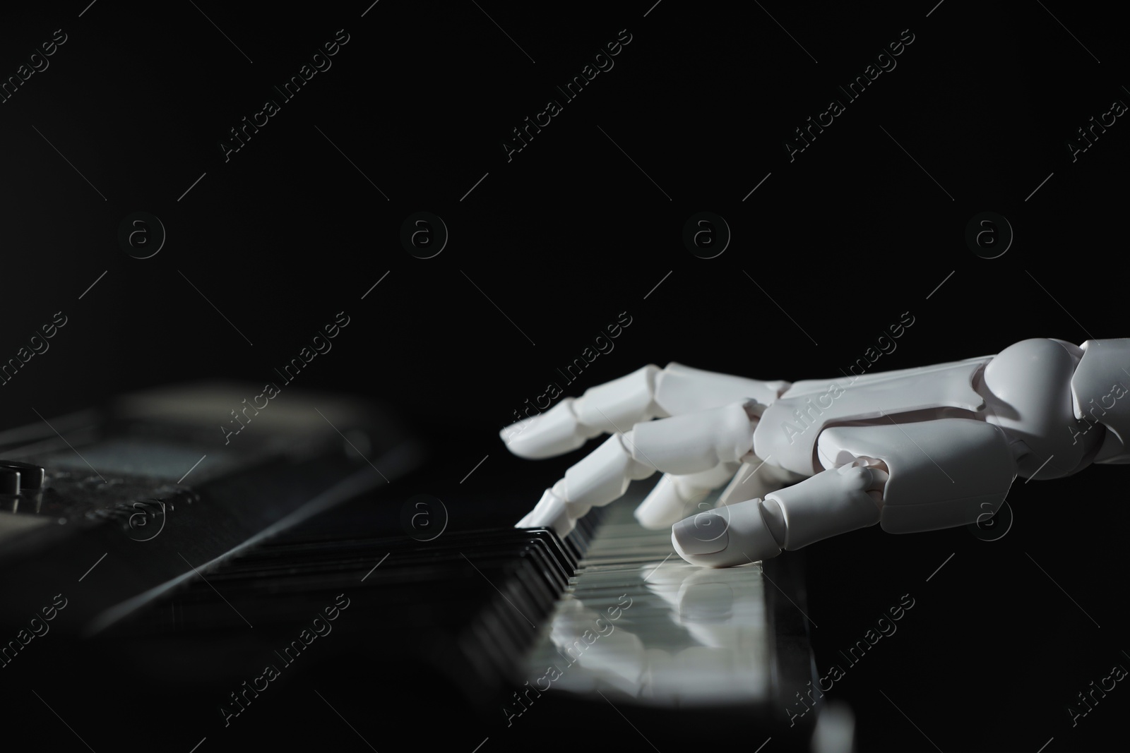 Photo of Artificial intelligence. Robot hand playing synthesizer on black background, closeup