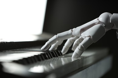 Photo of Artificial intelligence. Robot hand playing synthesizer on color background, closeup