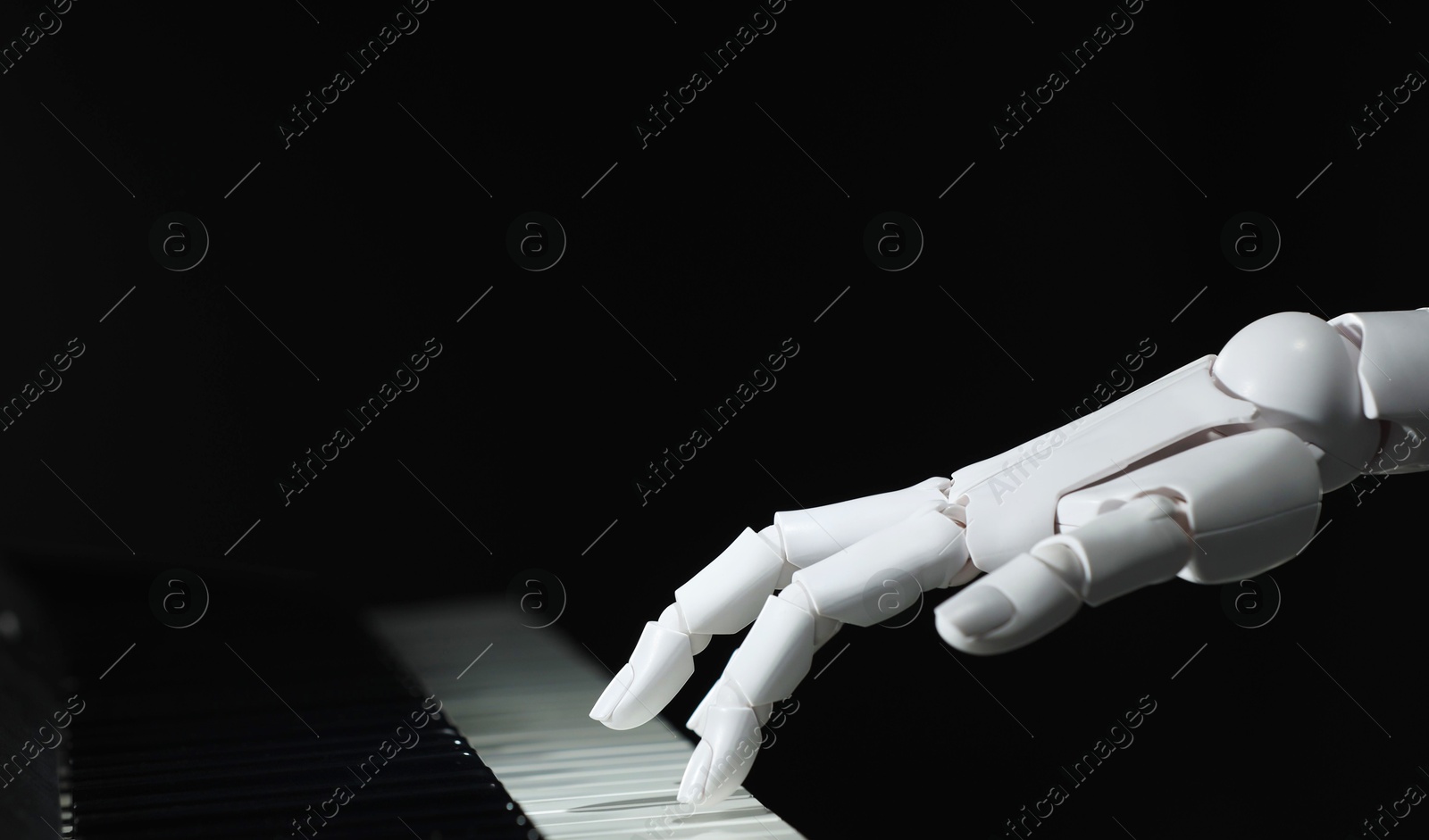 Photo of Artificial intelligence. Robot hand playing piano on black background, closeup