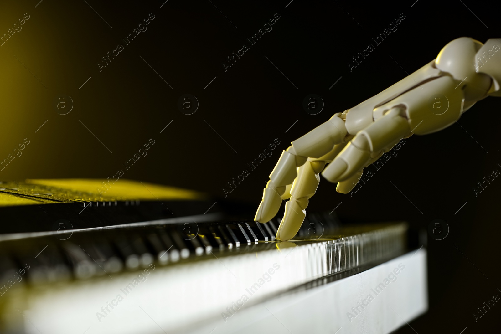 Photo of Artificial intelligence. Robot hand playing synthesizer on dark background, closeup