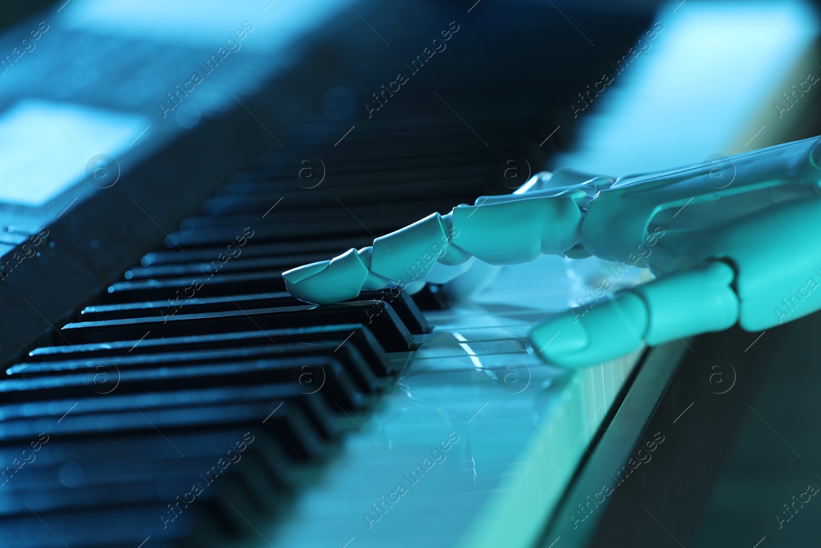 Photo of Artificial intelligence. Robot hand playing synthesizer in blue light, closeup