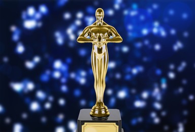 Image of Golden trophy in shape of human figure on dark blue background with blurred lights