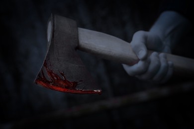 Image of Man holding bloody axe outdoors, closeup view