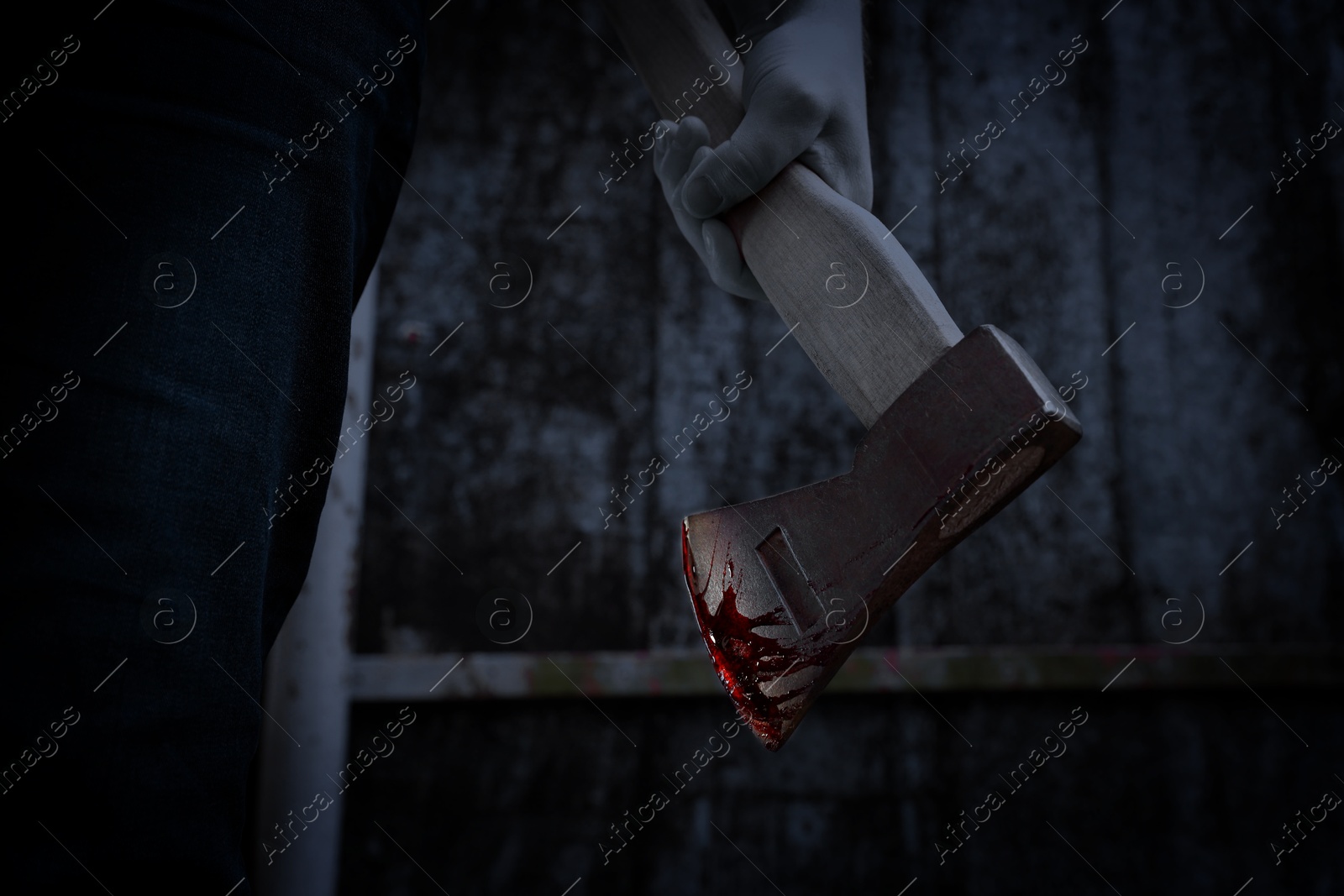 Image of Man holding bloody axe outdoors, closeup view