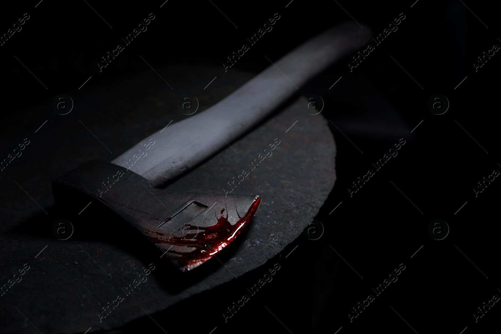 Image of Axe with blood on rusty metal surface in darkness, closeup