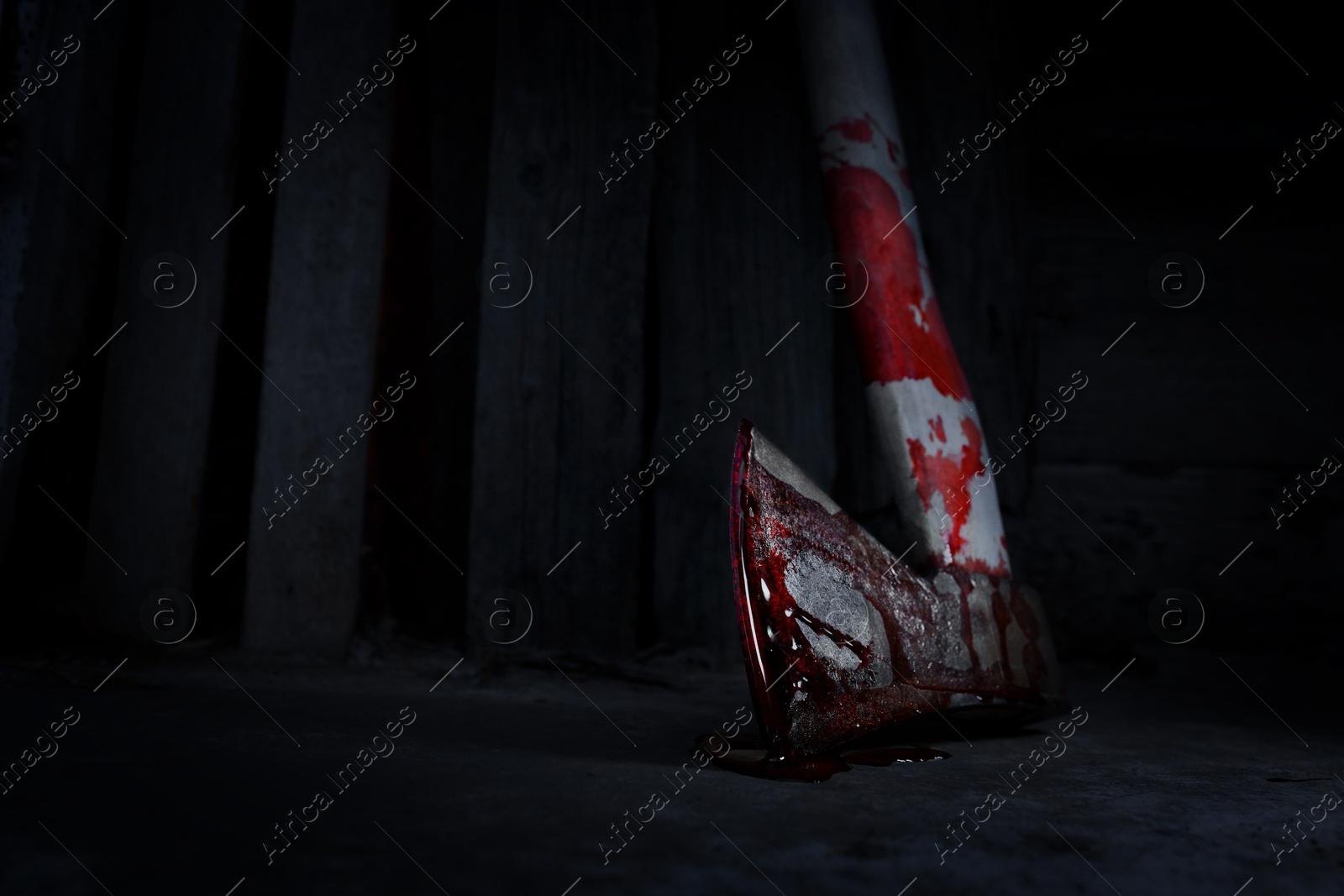 Image of Axe with blood on floor indoors, closeup