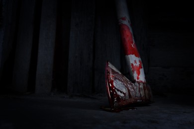 Image of Axe with blood on floor indoors, closeup