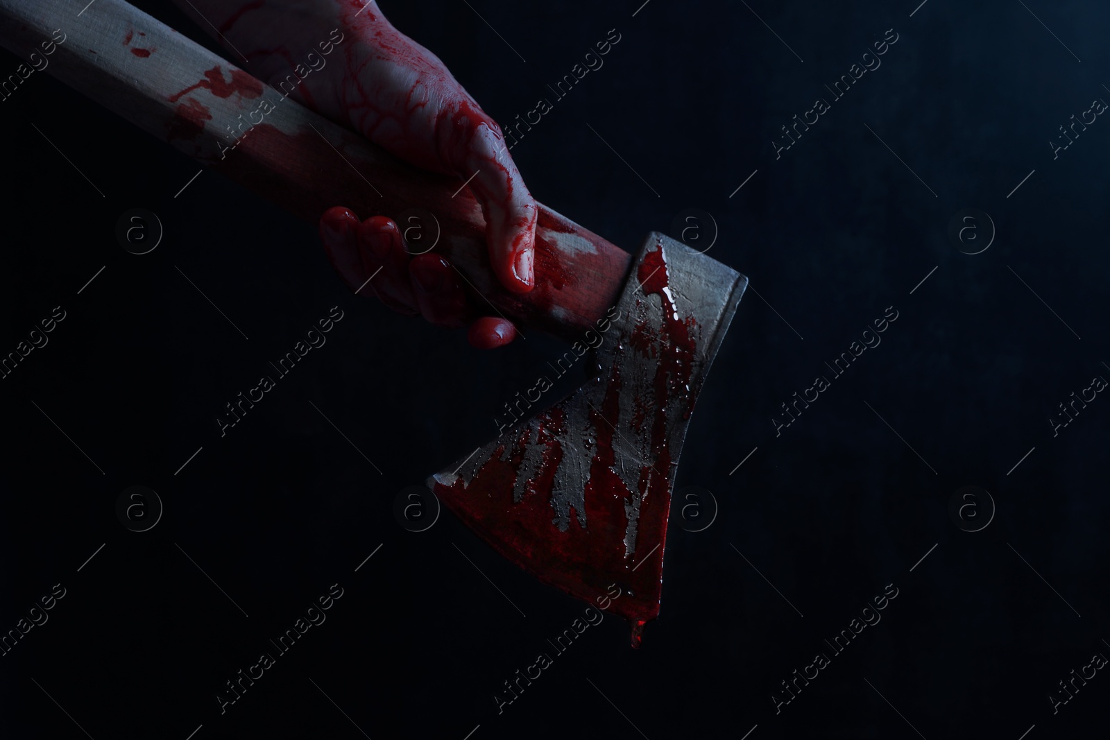 Image of Man holding bloody axe in darkness, closeup