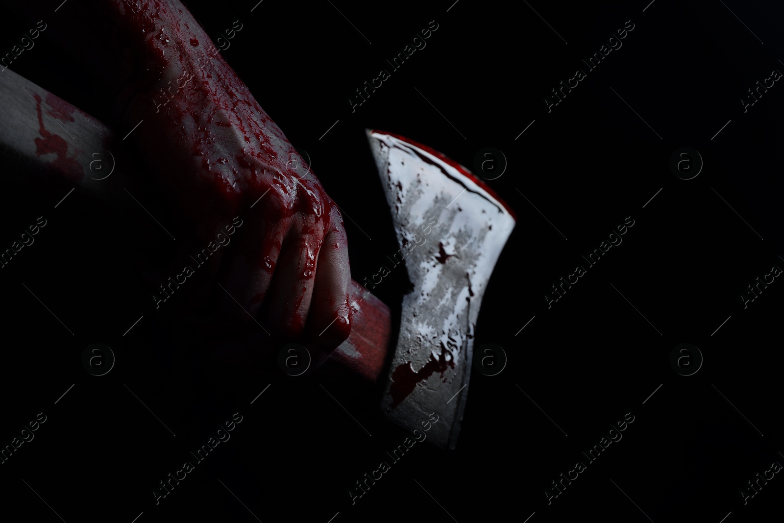 Image of Man holding bloody axe in darkness, closeup