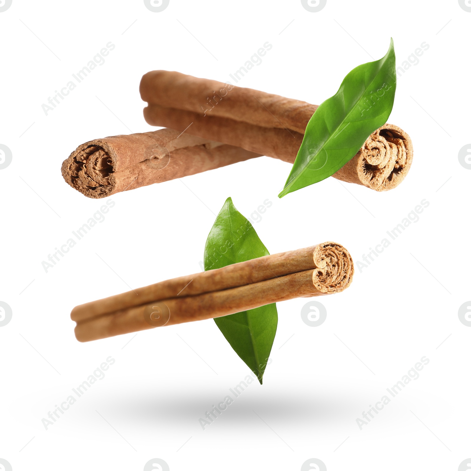 Image of Cinnamon sticks and green leaves in air on white background