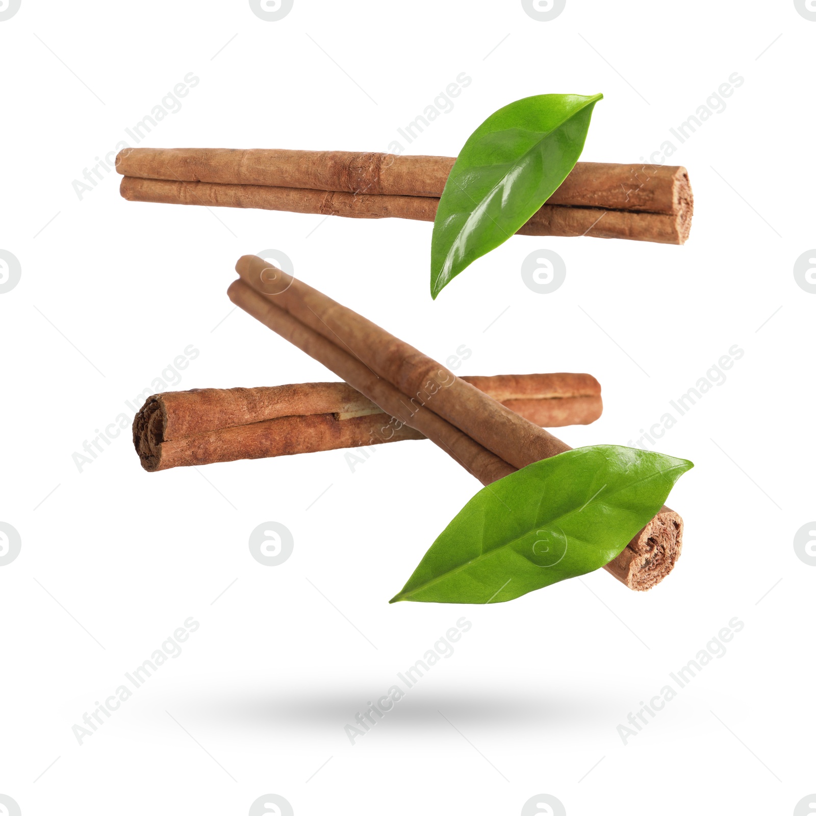 Image of Cinnamon sticks and green leaves in air on white background