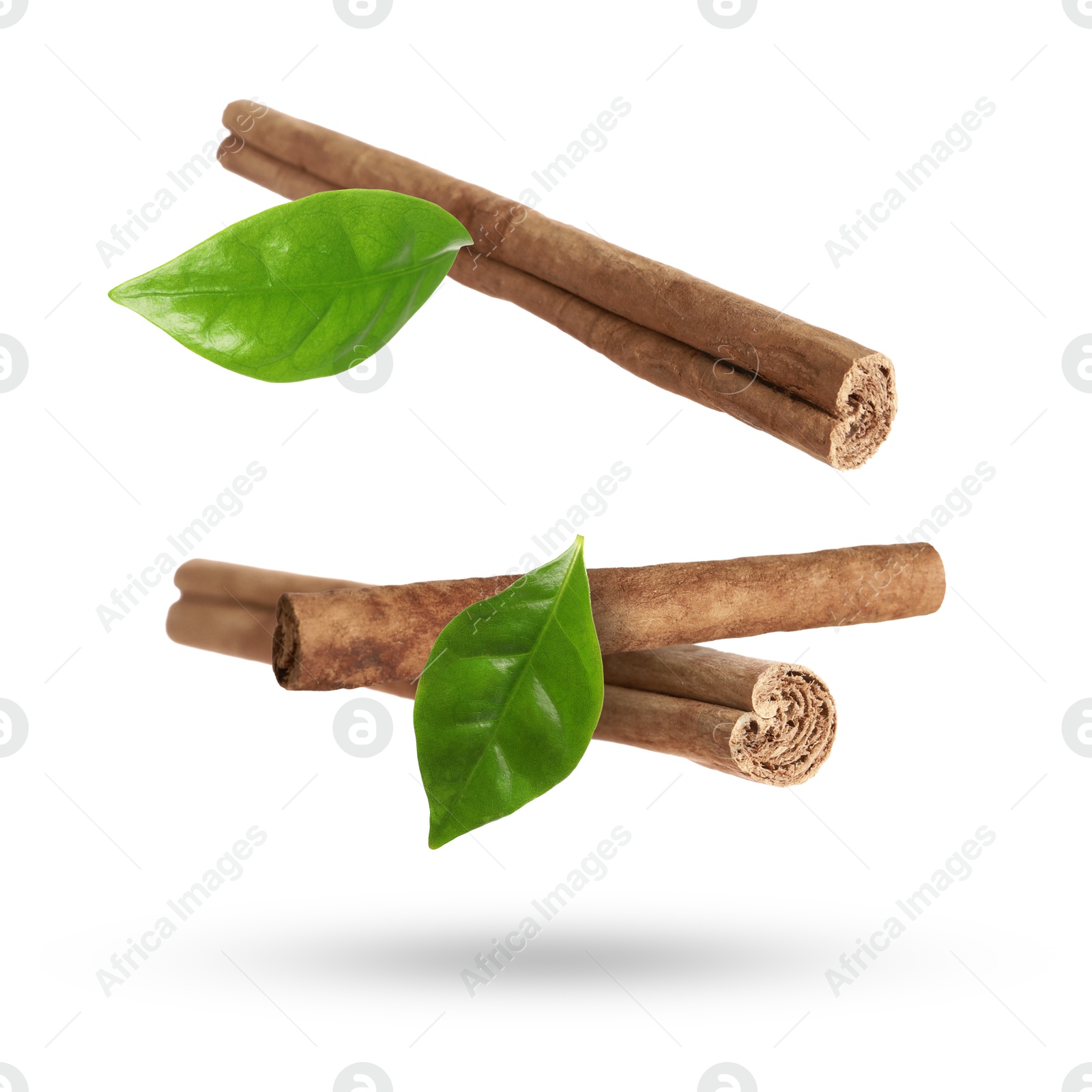 Image of Cinnamon sticks and green leaves in air on white background