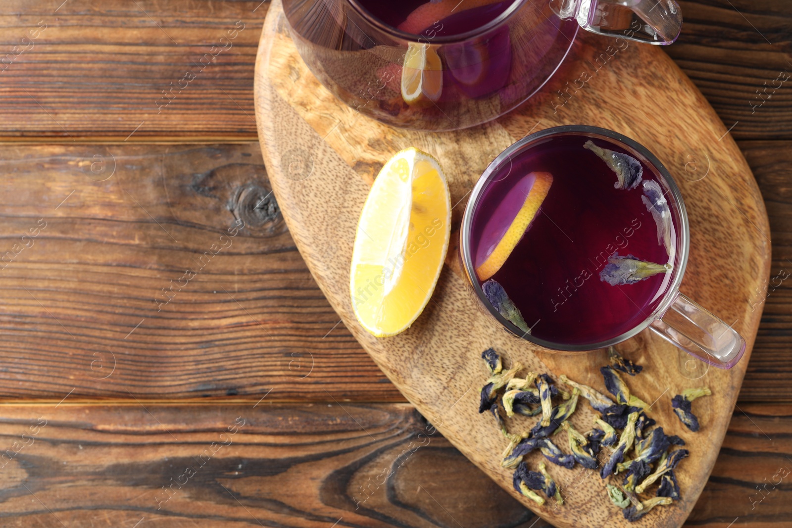 Photo of Delicious butterfly pea flower tea with lemon on wooden table, top view. Space for text