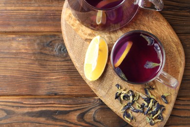 Photo of Delicious butterfly pea flower tea with lemon on wooden table, top view. Space for text