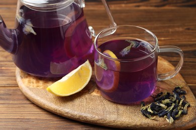 Photo of Delicious butterfly pea flower tea with lemon on wooden table, closeup