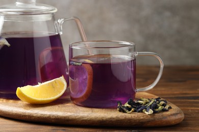 Photo of Delicious butterfly pea flower tea with lemon on wooden table, closeup