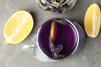 Photo of Delicious butterfly pea flower tea with lemon on gray textured table, flat lay