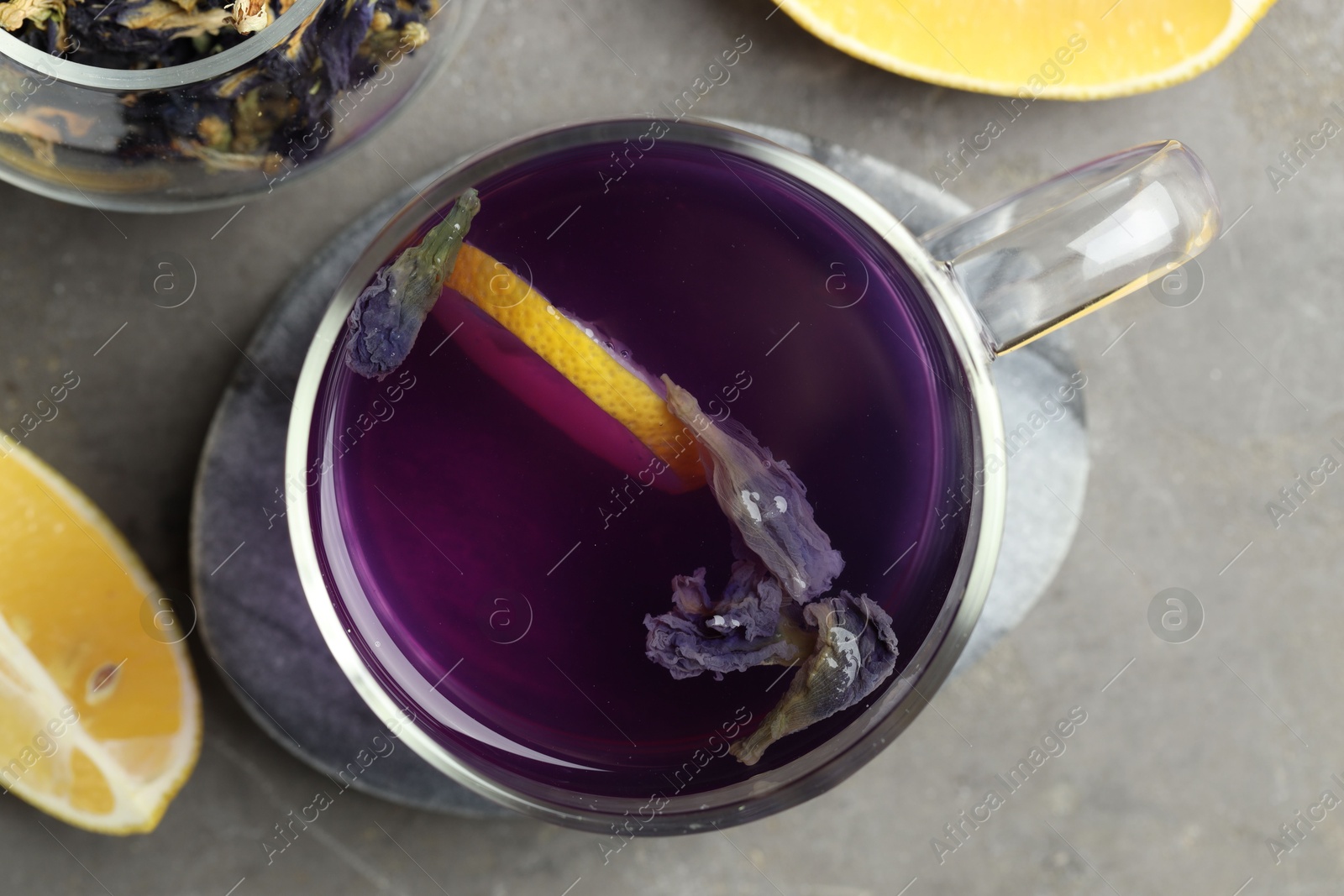 Photo of Delicious butterfly pea flower tea with lemon on gray textured table, flat lay