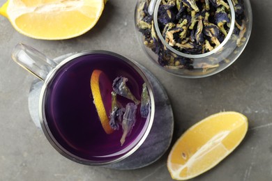 Photo of Delicious butterfly pea flower tea with lemon on gray textured table, flat lay