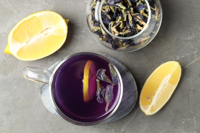 Photo of Delicious butterfly pea flower tea with lemon on gray textured table, flat lay