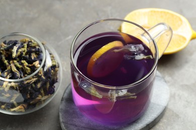 Photo of Delicious butterfly pea flower tea with lemon on gray table, closeup