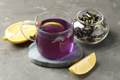 Photo of Delicious butterfly pea flower tea with lemon on gray textured table