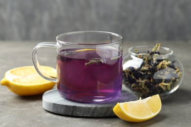 Photo of Delicious butterfly pea flower tea with lemon on gray textured table