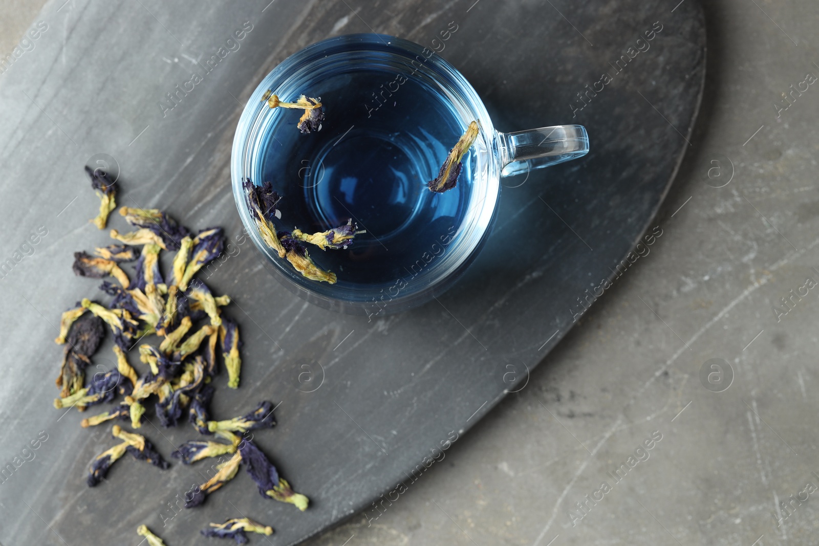 Photo of Delicious butterfly pea flower tea on gray textured table, top view