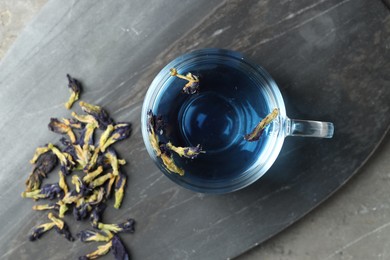 Photo of Delicious butterfly pea flower tea on gray textured table, top view