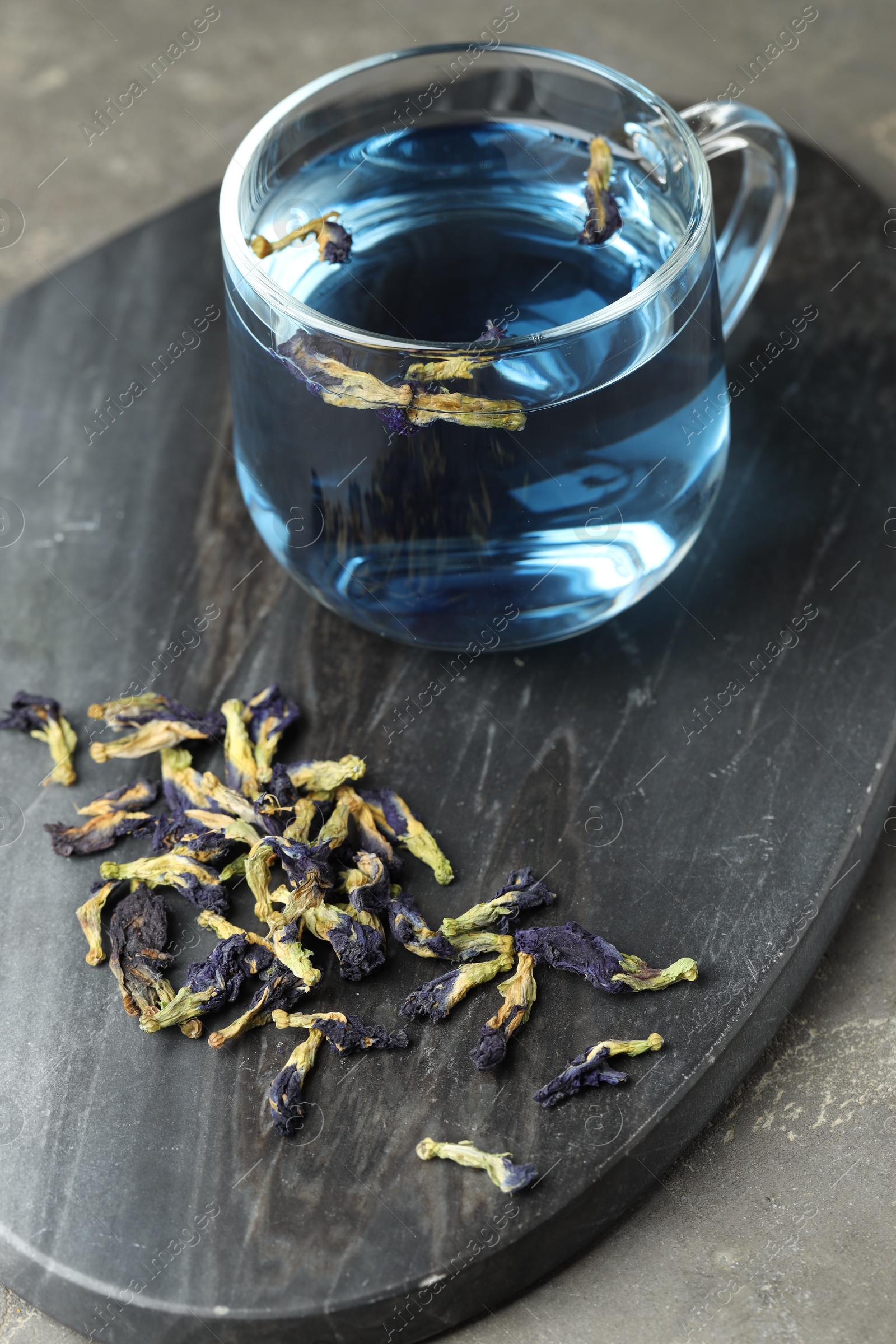 Photo of Delicious butterfly pea flower tea on gray textured table, closeup