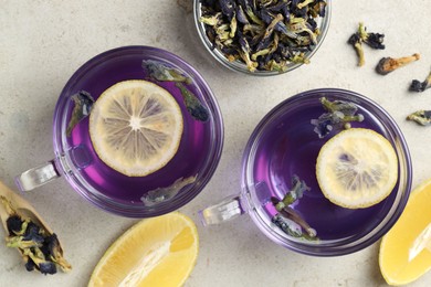 Photo of Delicious butterfly pea flower tea with lemon on gray textured table, flat lay