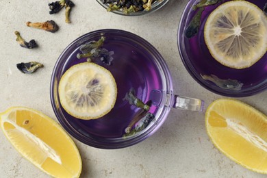 Photo of Delicious butterfly pea flower tea with lemon on gray textured table, flat lay