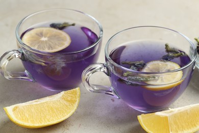 Photo of Delicious butterfly pea flower tea with lemon on gray textured table, closeup